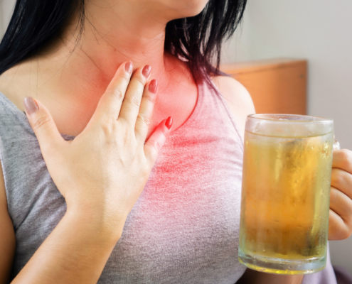 An image of a woman with acid reflux rubbing her reddened neck.