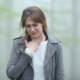 An image of a woman rubbing her sore throat in a foggy forest.